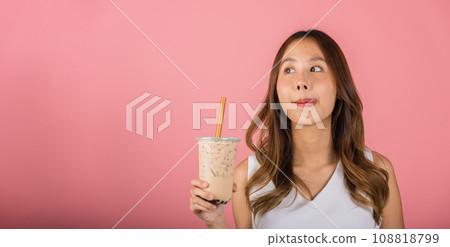 Asian woman holding drinking brown sugar flavored tapioca pearl bubble milk tea lick lips wanna taste have delighted summer holiday dream, smile female, isolated on pink background, beverage concept 108818799