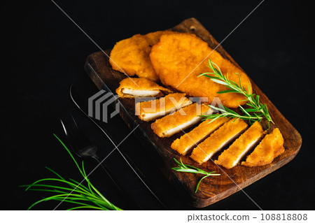 Semi-finished Chicken Breaded Fillet,Schnitzel.Chicken breaded schnitzels .Breaded Chicken Fillet on a dark Background, Chicken Breaded Raw Meat. Fast cooking.View from above.Half-finished. 108818808