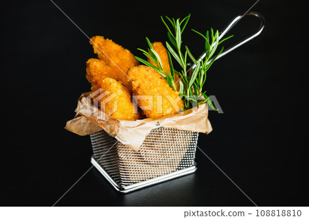 Semifinished chicken nuggets from chicken fillet on a dark background with fresh herbs. Quick cooking at home. Fast food. Breaded chicken nuggets. Breaded Chicken Inner Fillet. 108818810