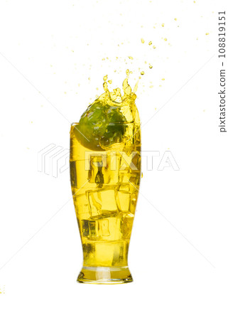 Splash spill lime juice down in ice cube glass, lime juice fall down in yellow liquid water. Green lime in juice throw splash in air. White background Isolated high speed shutter, freeze action Splash spill lime juice down in ice cube glass, lime juice fall down in yellow liquid water. Green lime in juice throw splash in air. White background Isolated high speed shutter, freeze action 108819151