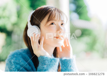 Young woman listening to music on the terrace Young woman listening to music on the terrace 108821278