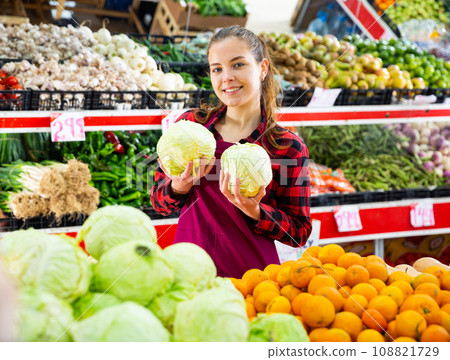 Portrait of a smiling girl of the seller holding a cabbage in her hands 108821729