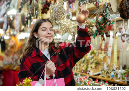 Cheerful girl viewing ball while walking at Christmas fair Cheerful girl viewing ball while walking at Christmas fair 108821802