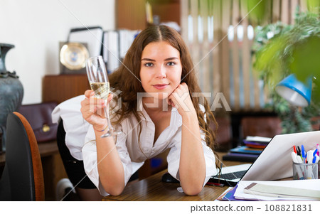 Portrait of a charming girl with a glass of wine in company office 108821831