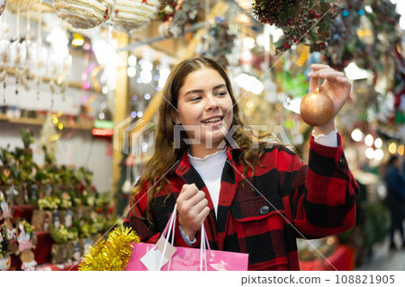 Smiling girl with golden bauble walking on Christmas fair 108821905