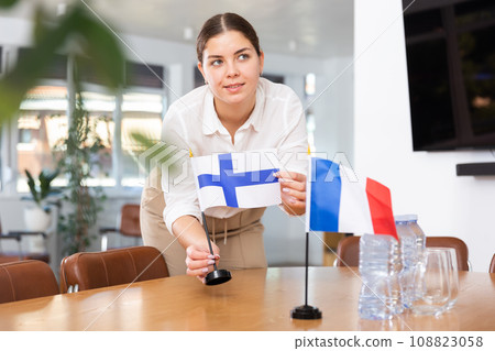 Employee of delegation prepares negotiating table - sets up flag of Finland and France 108823058