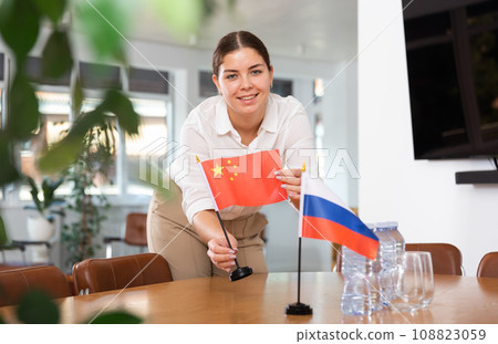 Preparing for business negotiations - woman sets small flags of countries of China and Russia on table 108823059