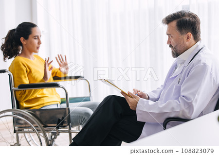 Psychiatrist doctor collect data talk with patient on wheelchair for mental care health problems check followup in hospital clinic 108823079