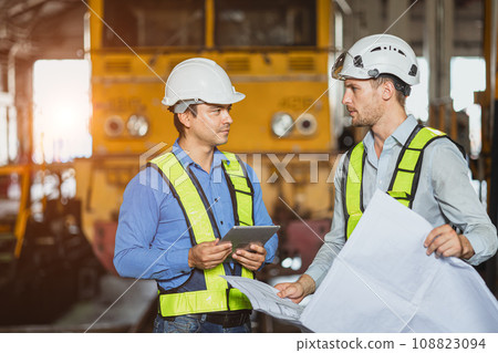 Engineer team smart young skill worker consulting supervisor working together with design floor plan in locomotive train depot workshop Engineer team smart young skill worker consulting supervisor working together with design floor plan in locomotive train depot workshop 108823094