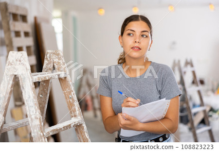 Portrait of woman filling documentation during repair works in construction site 108823223