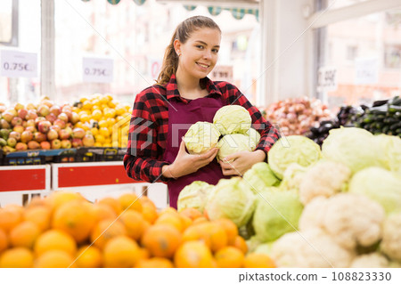 Portrait of a smiling girl of the seller holding a cabbage in her hands 108823330