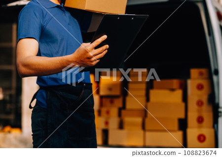 Asian delivery man in cargo van checking boxes. 108823674