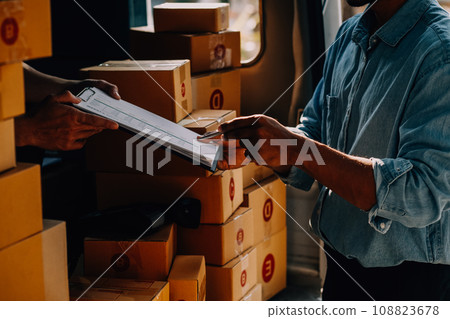 Asian delivery man in cargo van checking boxes. 108823678