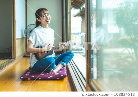 A woman playing the ukulele in a Japanese-style room 108824518