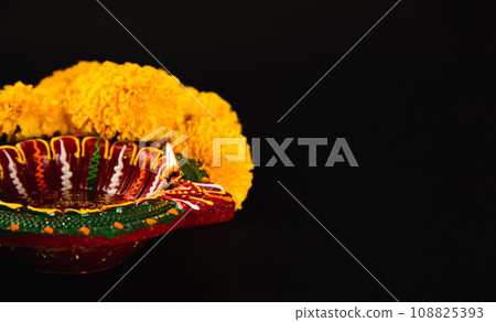 Elegance in Diwali, A stunning Diwali lamp and ornate flower rangoli set against a striking black backdrop. Perfect for Diwali, wedding invitations, and cultural celebrations. 108825393