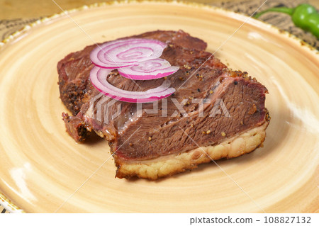 Juicy Steak with Caramelized Onions Served on a Gleaming White Plate. Selective focus Juicy Steak with Caramelized Onions Served on a Gleaming White Plate. Selective focus 108827132