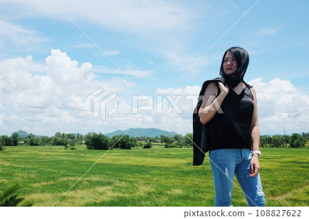 Asian sexy woman in black shirt and wear jean standing in grassland and mountain with cloud in the blue sky on summer season. Asian sexy woman in black shirt and wear jean standing in grassland and mountain with cloud in the blue sky on summer season. 108827622