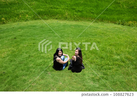 Asian Couple sexy woman in black shirt with jean and dress sitting on grass field on mountain in summer season. Asian Couple sexy woman in black shirt with jean and dress sitting on grass field on mountain in summer season. 108827623