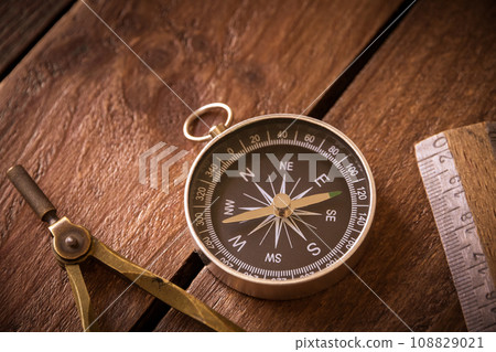 Vintage rule, drawing and navigational Compass on a rustic wooden board 108829021