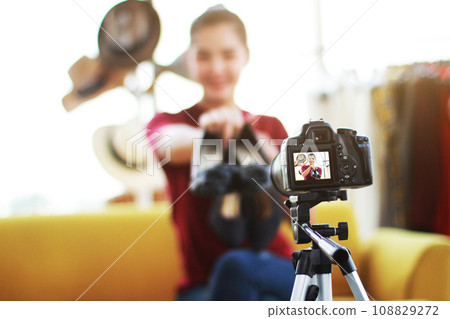 Beautiful Asian woman blogger recording on video Dslr Camera for selling shoes online shopping on website. Marketing in social media concept. Close up and focus on Dslr Camera. Beautiful Asian woman blogger recording on video Dslr Camera for selling shoes online shopping on website. Marketing in social media concept. Close up and focus on Dslr Camera. 108829272