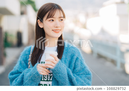 A woman strolling around town while holding coffee 108829732