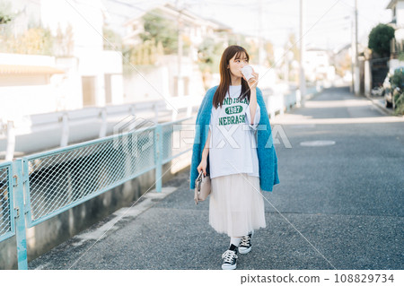 A woman strolling around town while holding coffee 108829734