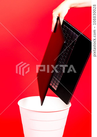 Black laptop in a trash bin on a red background isolated Black laptop in a trash bin on a red background isolated 108830028