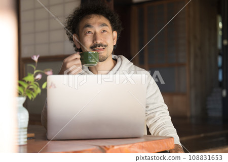 A man working on a computer in an old folk house A man working on a computer in an old folk house 108831653