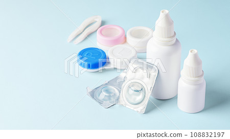 Contact lenses, solution bottle and eye drops with accessories on blue background, copy space Contact lenses, solution bottle and eye drops with accessories on blue background, copy space 108832197