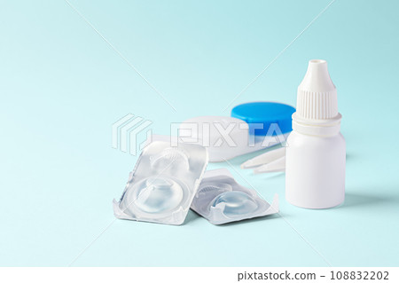 Contact lenses with eye drops and accessories on blue background, copy space Contact lenses with eye drops and accessories on blue background, copy space 108832202