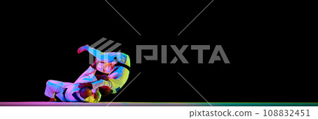 Banner. Two men Judoist training, fighting showing technical skill in neon light isolated black studio background. Copy space for ad, text 108832451