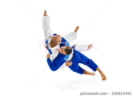 Portrait of two athletic, strong men, professional judokas, fighters showing their skills while competition isolated white background. 108832491