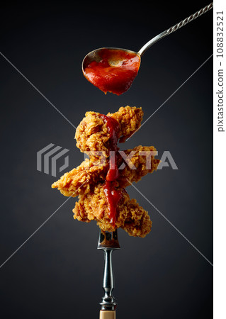 Fried chicken with ketchup on a fork. 108832521