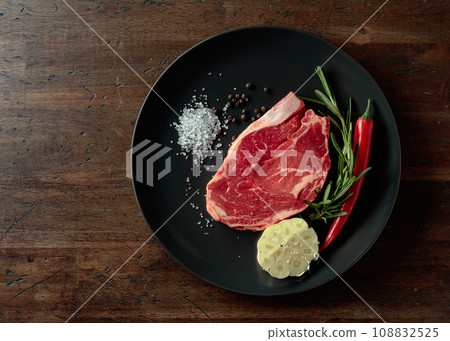 Raw beef steak with rosemary, garlic, salt, and pepper. Raw beef steak with rosemary, garlic, salt, and pepper. 108832525