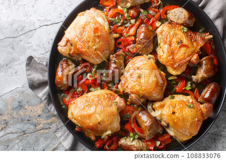 Chicken Scarpariello classic that combines chicken, onion, sausage, and spicy cherry peppers, all in a pungent vinegar sauce closeup on the plate. Horizontal top view 108833076