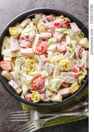 Salad version of the viral grinder sandwich made with a delicious creamy dressing, crunchy lettuce, deli meat, and cheese closeup on the plate. Vertical top view 108833096