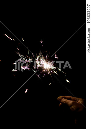 Female hand holding a burning sparkler. 108833997