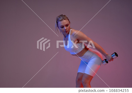 awesome sporty girl bending her back toward, looking back at dumbbells 108834255