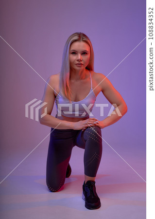 beautiful well-built woman sitting on one leg, putting her hand on knee 108834352