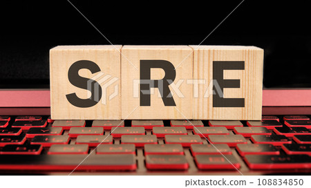 SRE. Site Reliability Engineering written on wooden cubes on the laptop keyboard 108834850