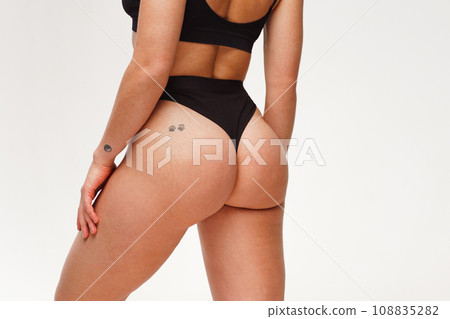 A woman with a beautiful feminine figure in black lingerie with overweight, cellulite and stretch marks.  108835282
