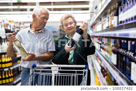 Mature couple chooses bottle of wine in alcohol section of supermarket 108837482