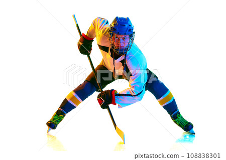 Goalkeeper. Concentrated young girl, hockey payer ion motion, standing with stick during game against white background in neon light 108838301