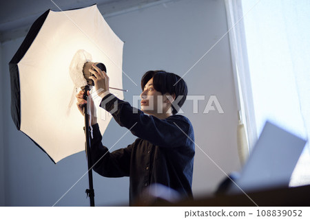 A Japanese photographer adjusting a strobe in a photo studio 108839052