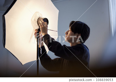 A Japanese photographer adjusting a strobe in a photo studio 108839053
