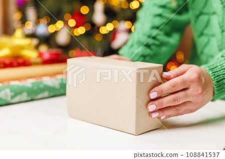 Young woman wrapping gifts at table in living room Young woman wrapping gifts at table in living room 108841537