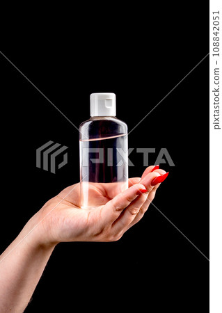 Plastic bottle with hand sanitizer gel on a woman's palm. 108842051
