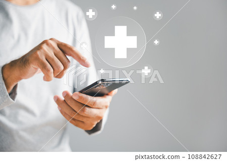 Mobile phone in man hand displays plus icon, symbolizing healthcare additions. Health insurance and medical benefits concept. Access to welfare health with background copy space. 108842627