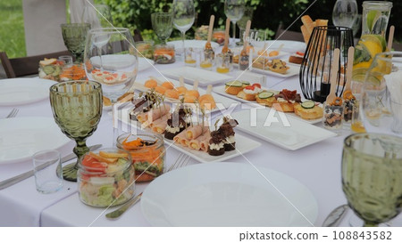Beautifully decorated banquet table with appetizers. Business lunch. A beautiful festive table covered with a variety of food. Food and drinks on the festive table in the restaurant. Beautifully decorated banquet table with appetizers. Business lunch. A beautiful festive table covered with a variety of food. Food and drinks on the festive table in the restaurant. 108843582