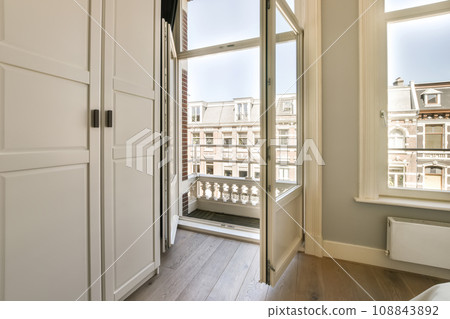 a room with wooden floors and white walls, there is an open door that leads out to the balcony area a room with wooden floors and white walls, there is an open door that leads out to the balcony area 108843892